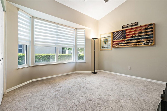 carpeted spare room with a healthy amount of sunlight, baseboards, and vaulted ceiling