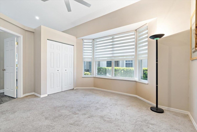 unfurnished bedroom featuring a closet, baseboards, carpet floors, and ceiling fan