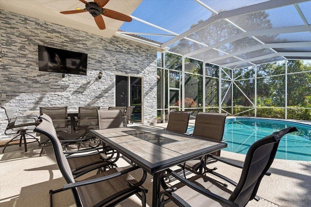 view of patio featuring a lanai, outdoor dining space, an outdoor pool, and a ceiling fan