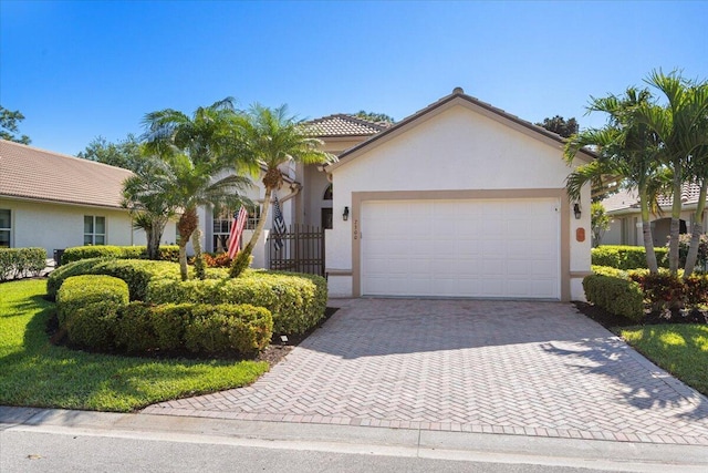 view of front of house featuring stucco siding, decorative driveway, a garage, and a tiled roof