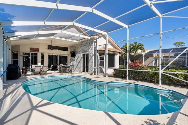 pool featuring glass enclosure, a patio, and ceiling fan