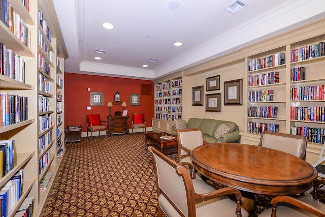 sitting room featuring visible vents, crown molding, carpet, bookshelves, and built in features