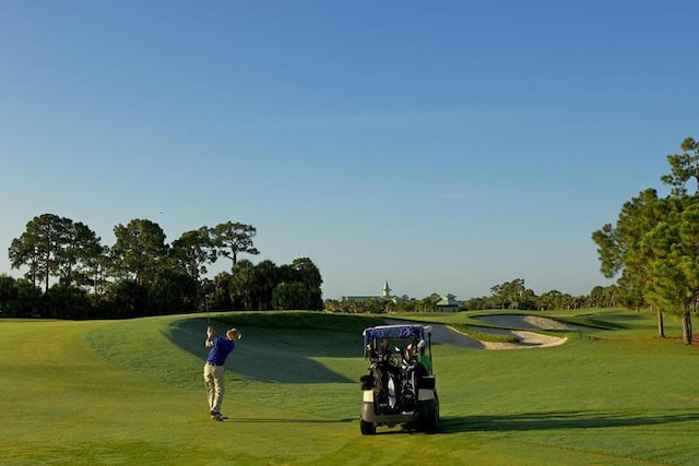 view of home's community with view of golf course and a lawn