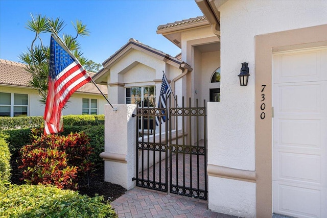 property entrance featuring stucco siding, a garage, and a gate