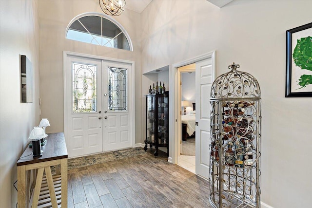 foyer with french doors, wood finished floors, and a towering ceiling