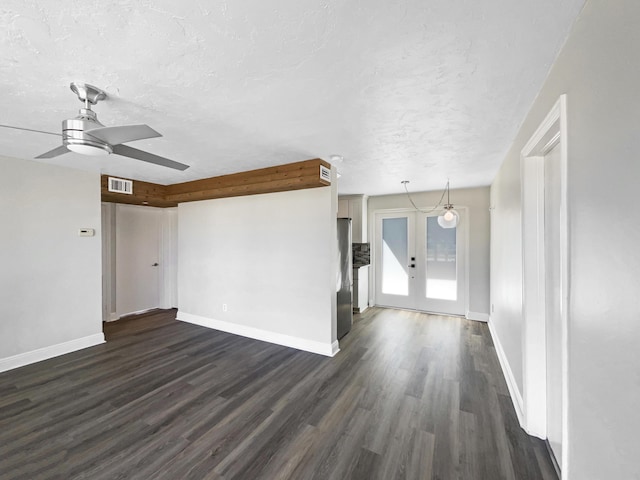 unfurnished living room with visible vents, a textured ceiling, dark wood-style flooring, and french doors