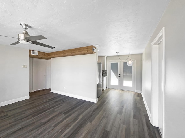 unfurnished living room with dark wood-style floors, visible vents, a textured ceiling, and baseboards