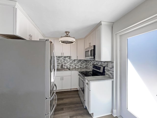 kitchen with dark wood-type flooring, a sink, tasteful backsplash, stainless steel appliances, and white cabinets