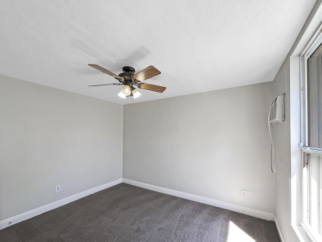 empty room with ceiling fan, baseboards, dark colored carpet, and a wall mounted AC