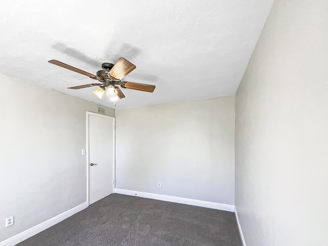 spare room with visible vents, a ceiling fan, baseboards, and dark carpet