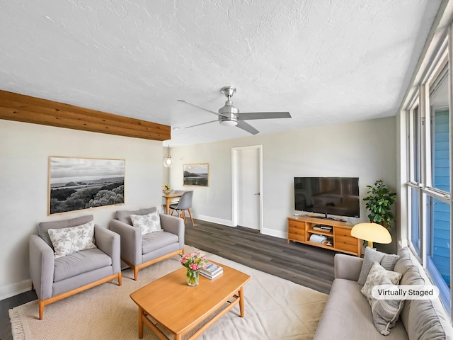 living area with a ceiling fan, wood finished floors, baseboards, and a textured ceiling