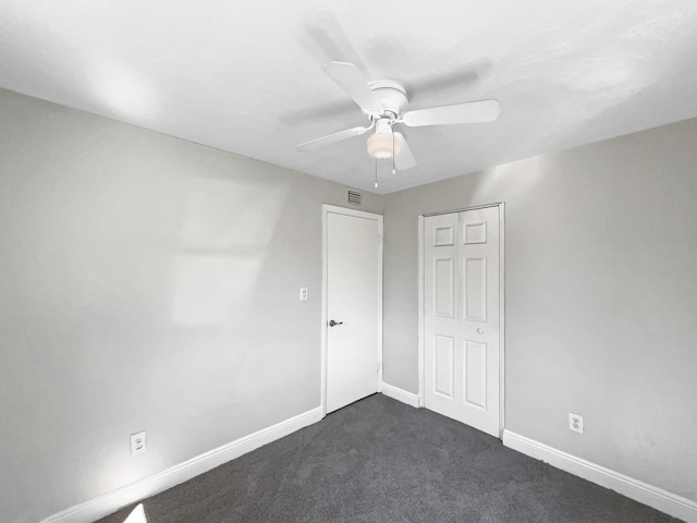 unfurnished bedroom featuring a ceiling fan, visible vents, baseboards, and dark carpet