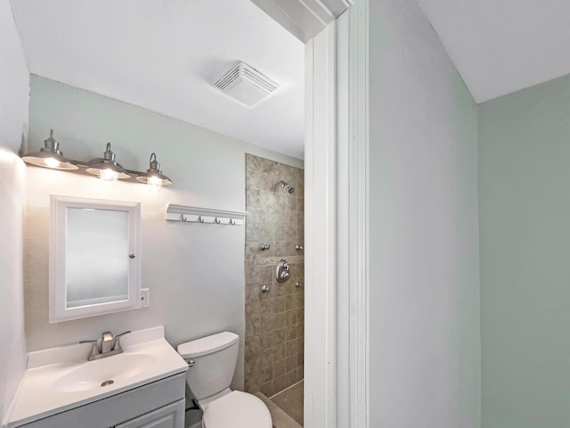 full bath featuring visible vents, tiled shower, toilet, and vanity