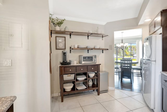 5801 Camino Del Sol Unit 102, Boca Raton, FL 33433 - kitchen with crown molding, a chandelier, light tile patterned floors, electric panel, and freestanding refrigerator