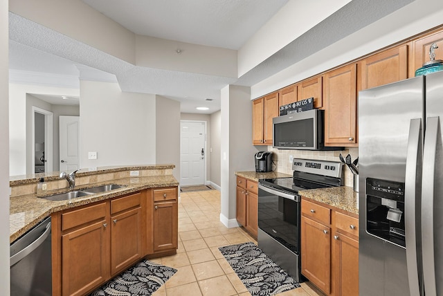 kitchen with tasteful backsplash, light tile patterned floors, brown cabinets, stainless steel appliances, and a sink