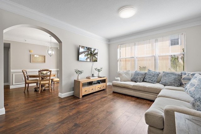 living area with arched walkways, crown molding, and dark wood-type flooring