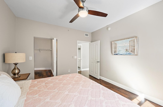 bedroom with a ceiling fan, baseboards, visible vents, dark wood finished floors, and a spacious closet