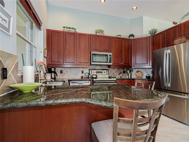 kitchen with backsplash, dark brown cabinets, a breakfast bar area, and stainless steel appliances