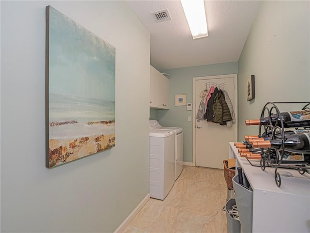 laundry area with visible vents, baseboards, separate washer and dryer, cabinet space, and a textured ceiling