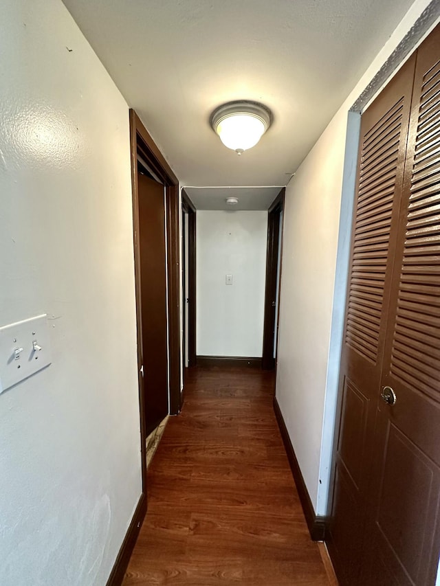 hallway with baseboards and dark wood-style flooring