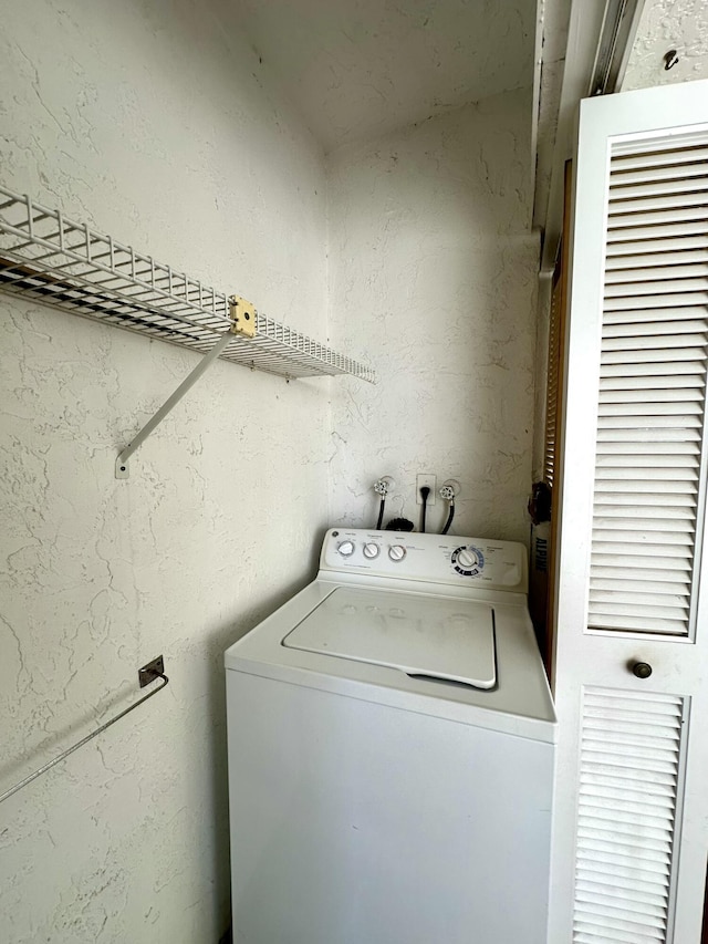 clothes washing area featuring laundry area, washer / clothes dryer, and a textured wall