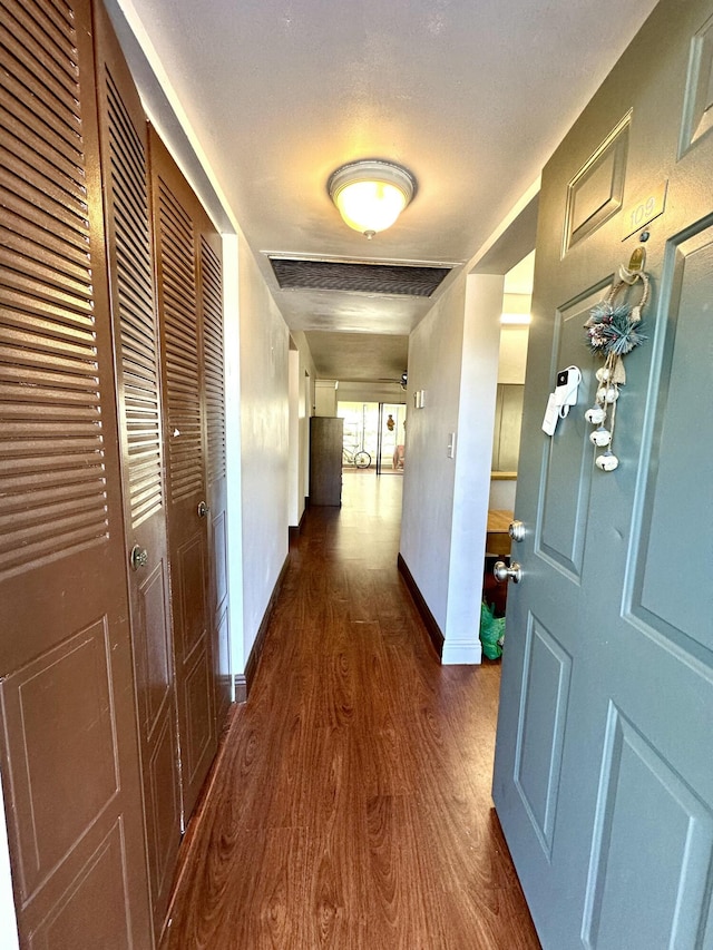 corridor featuring dark wood-style floors, visible vents, and baseboards