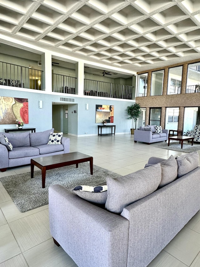 tiled living area featuring visible vents, baseboards, a high ceiling, and coffered ceiling