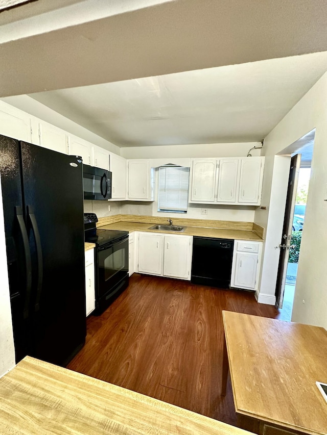 kitchen featuring dark wood finished floors, a sink, black appliances, light countertops, and white cabinetry