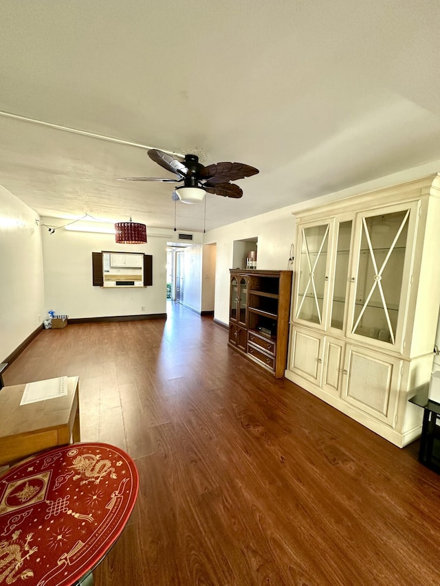 unfurnished living room featuring a ceiling fan, wood finished floors, and baseboards