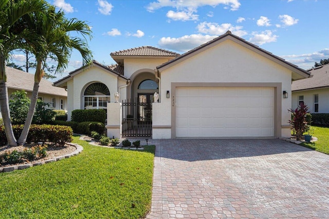 mediterranean / spanish house with stucco siding, a front lawn, a garage, a tiled roof, and decorative driveway