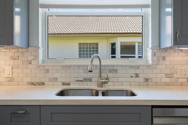 kitchen featuring a sink, tasteful backsplash, and gray cabinetry