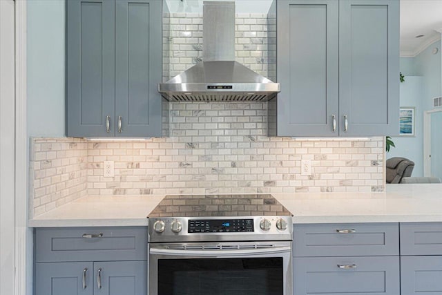 kitchen featuring wall chimney exhaust hood, backsplash, and stainless steel range with electric cooktop