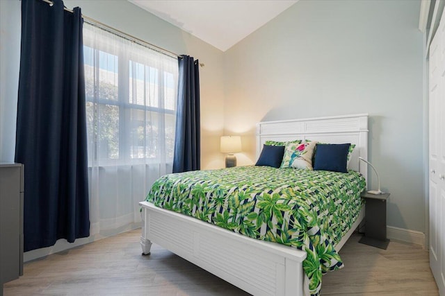 bedroom with wood finished floors, baseboards, and vaulted ceiling