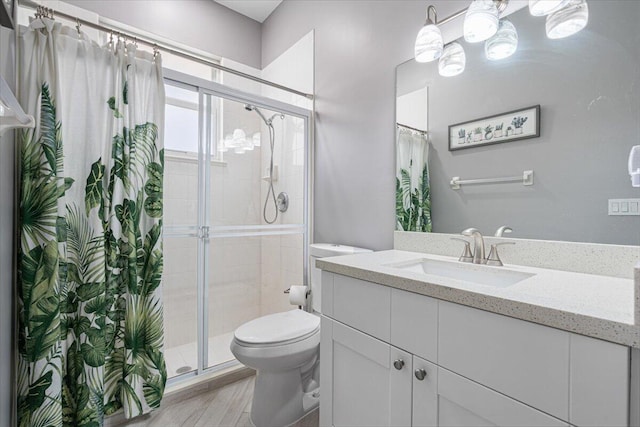 bathroom with wood finished floors, toilet, a stall shower, and vanity