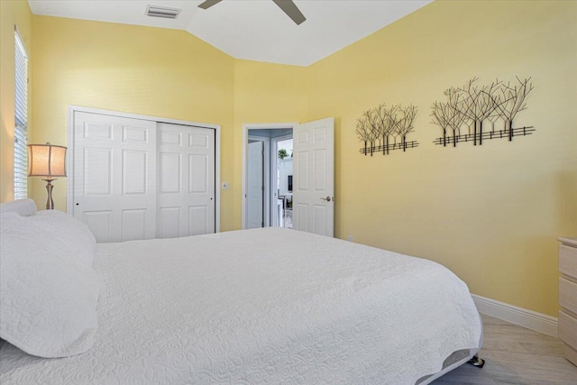 bedroom featuring visible vents, baseboards, vaulted ceiling, wood finished floors, and a closet