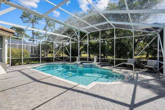 view of pool featuring glass enclosure, a patio area, and a pool with connected hot tub