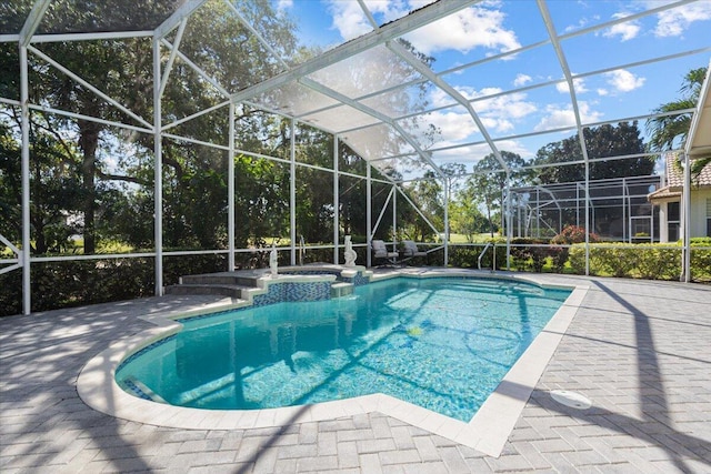 view of swimming pool with a patio area, glass enclosure, and a pool with connected hot tub