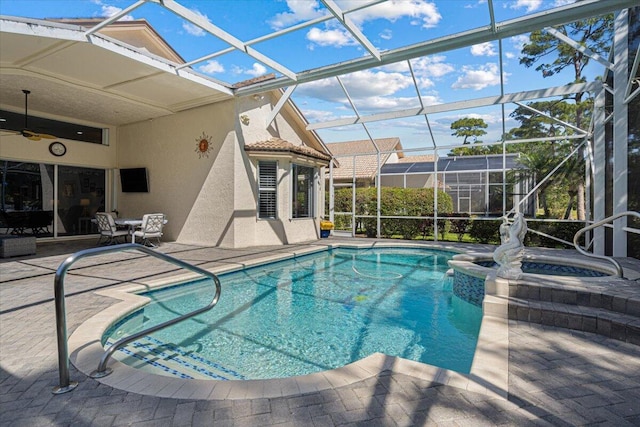 view of swimming pool with glass enclosure, a patio, a pool with connected hot tub, and ceiling fan