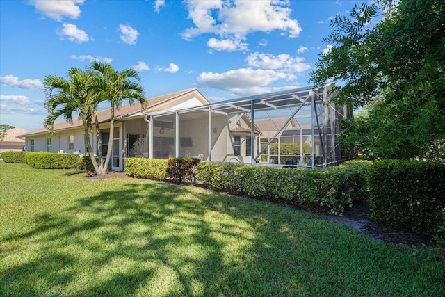 rear view of property featuring a lawn and a lanai