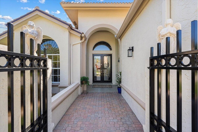 property entrance featuring stucco siding, fence, and french doors