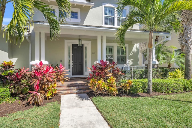 view of exterior entry with covered porch and stucco siding