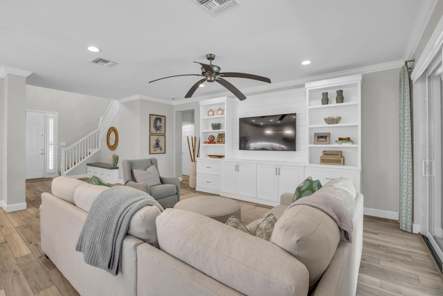 living room with stairway, visible vents, light wood finished floors, ceiling fan, and crown molding