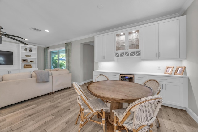 dining area with light wood-type flooring, visible vents, beverage cooler, ornamental molding, and baseboards