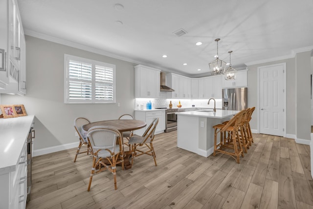 kitchen featuring backsplash, stainless steel appliances, wall chimney range hood, and ornamental molding