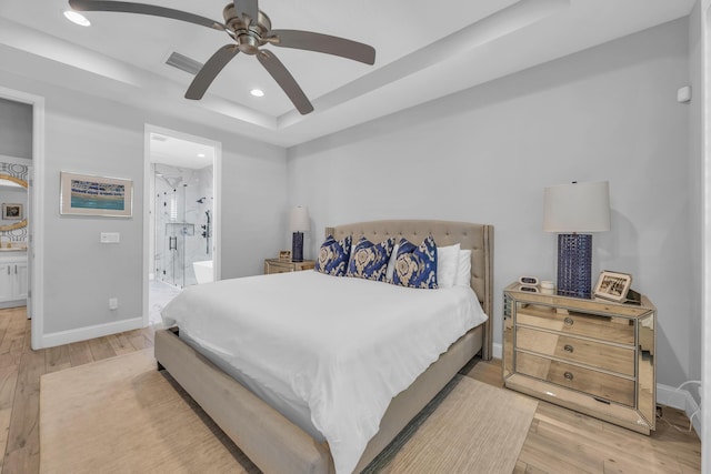 bedroom featuring light wood finished floors, recessed lighting, baseboards, and a tray ceiling