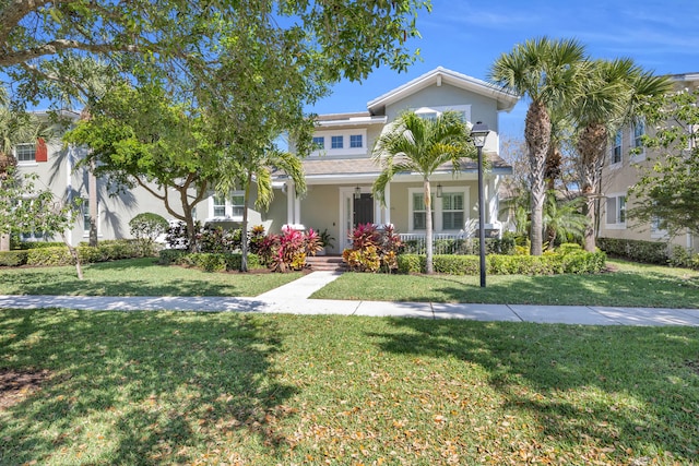 view of front facade with a front yard, a porch, and stucco siding