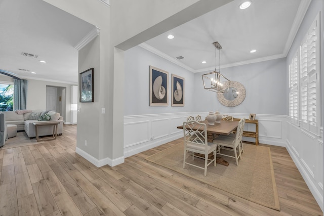 dining room featuring visible vents, recessed lighting, crown molding, a decorative wall, and light wood-type flooring