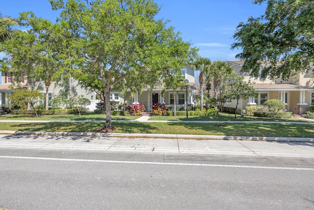 view of property hidden behind natural elements featuring a front lawn and stucco siding