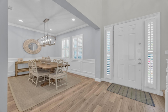 entryway with light wood-style flooring, wainscoting, visible vents, and ornamental molding