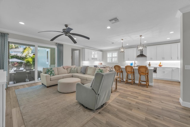 living area featuring a ceiling fan, visible vents, recessed lighting, ornamental molding, and light wood-type flooring